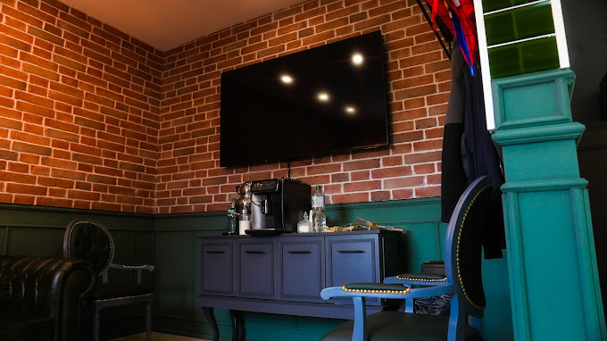 Wartebereich im Barbarossa Barbershop mit Fernseher, Kaffeemaschine und Sitzgelegenheiten.